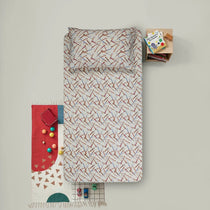 Patterned duvet cover set on a bed with toys and books on a light gray background