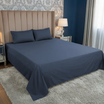 Blue bedspread on a bed in a bedroom with decorative headboard and lamps.