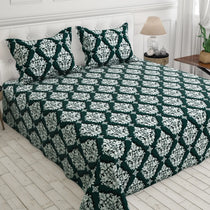 Green and white patterned bedspread on a bed with matching pillows.