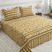 A yellow bedding set with a white and black floral print, striped borders, and matching pillowcases, displayed on a bed in a bright bedroom setting.