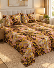 A bed dressed in a pink, gold, and brown abstract marble-patterned bedding set, including a comforter and two matching pillowcases, styled in a warm, modern bedroom setting.