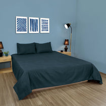Bedroom with a bed covered in a dark green comforter, nightstands, and wall art.
