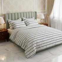 Striped bedding on a bed in a bedroom setting with lamps and curtains.