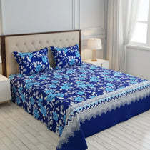 Blue floral bedspread with matching pillows on a bed in a bedroom setting.