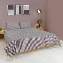 Bed with chevron patterned bedding in a bedroom setting.